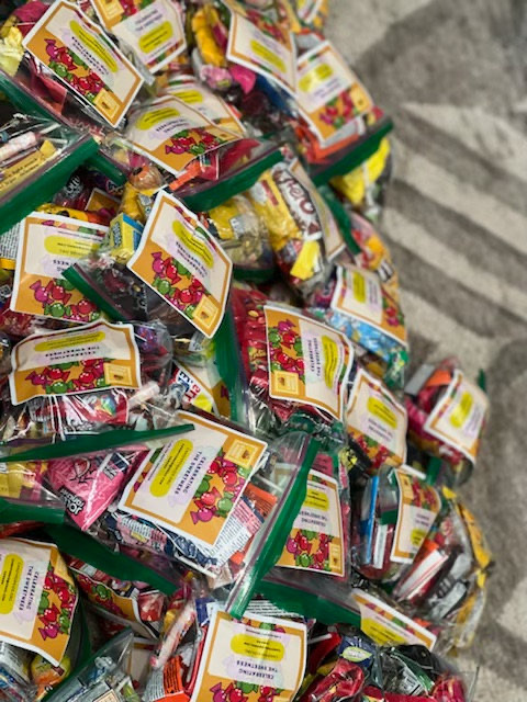 A pile of CandyForKids goodie bags filled with wrapped candy